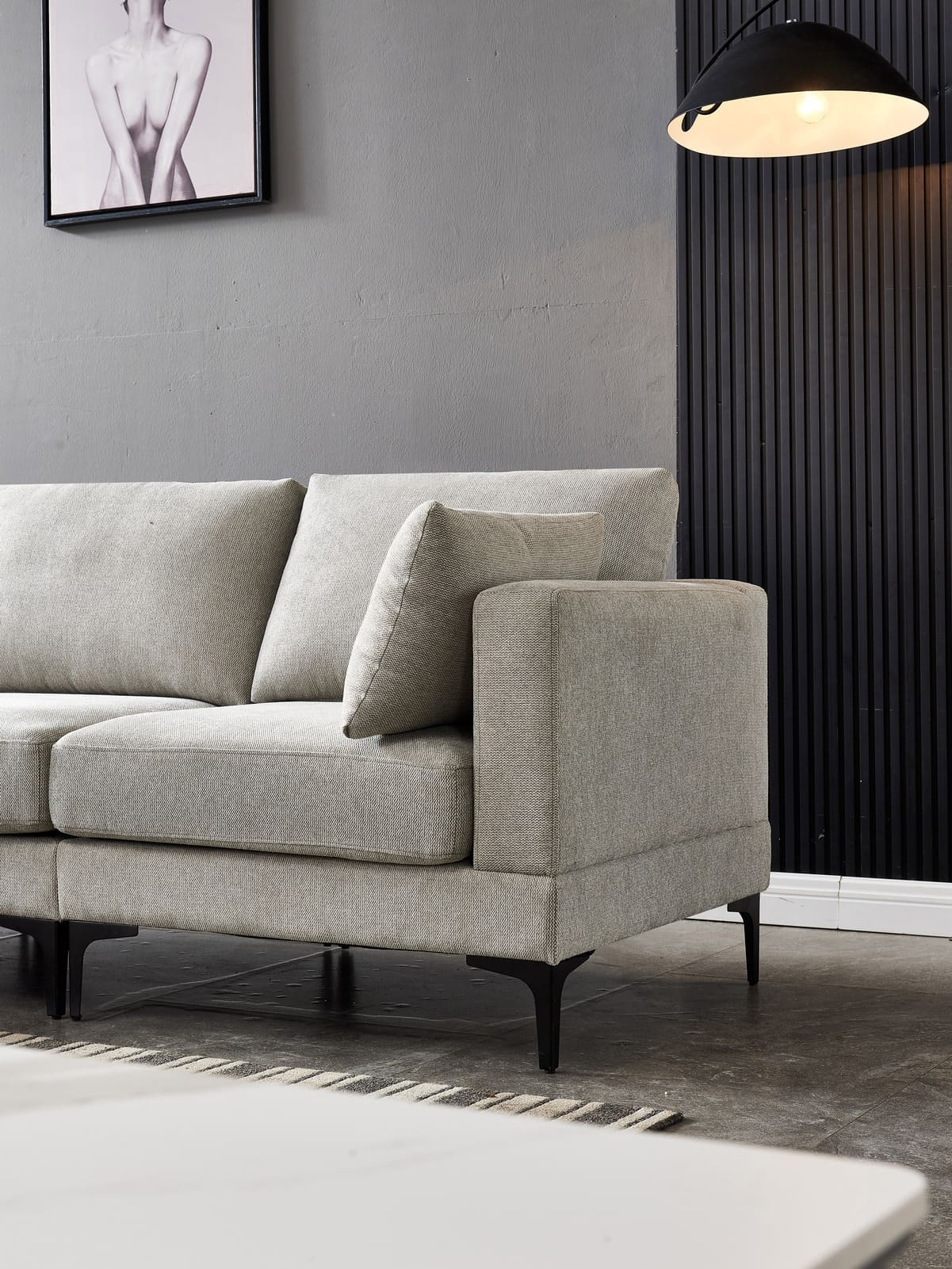 Anek Three Seater Grey Fabric Sofa with black metal legs on concrete floor, modern pendant lamp and grey walls